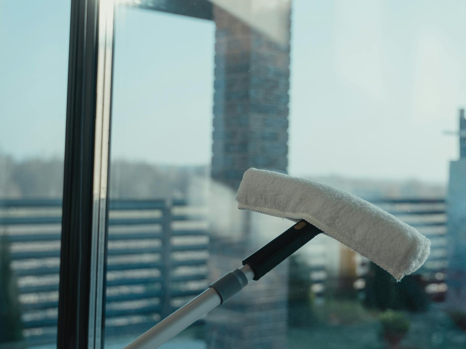 Glasreinigung an einem Hochhausfenster mit Blick auf die Stadt